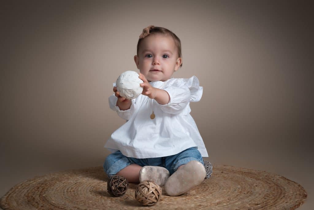 Bébé de 8 mois assis seul, jouant avec une boule, séance photo bébé près de Caen